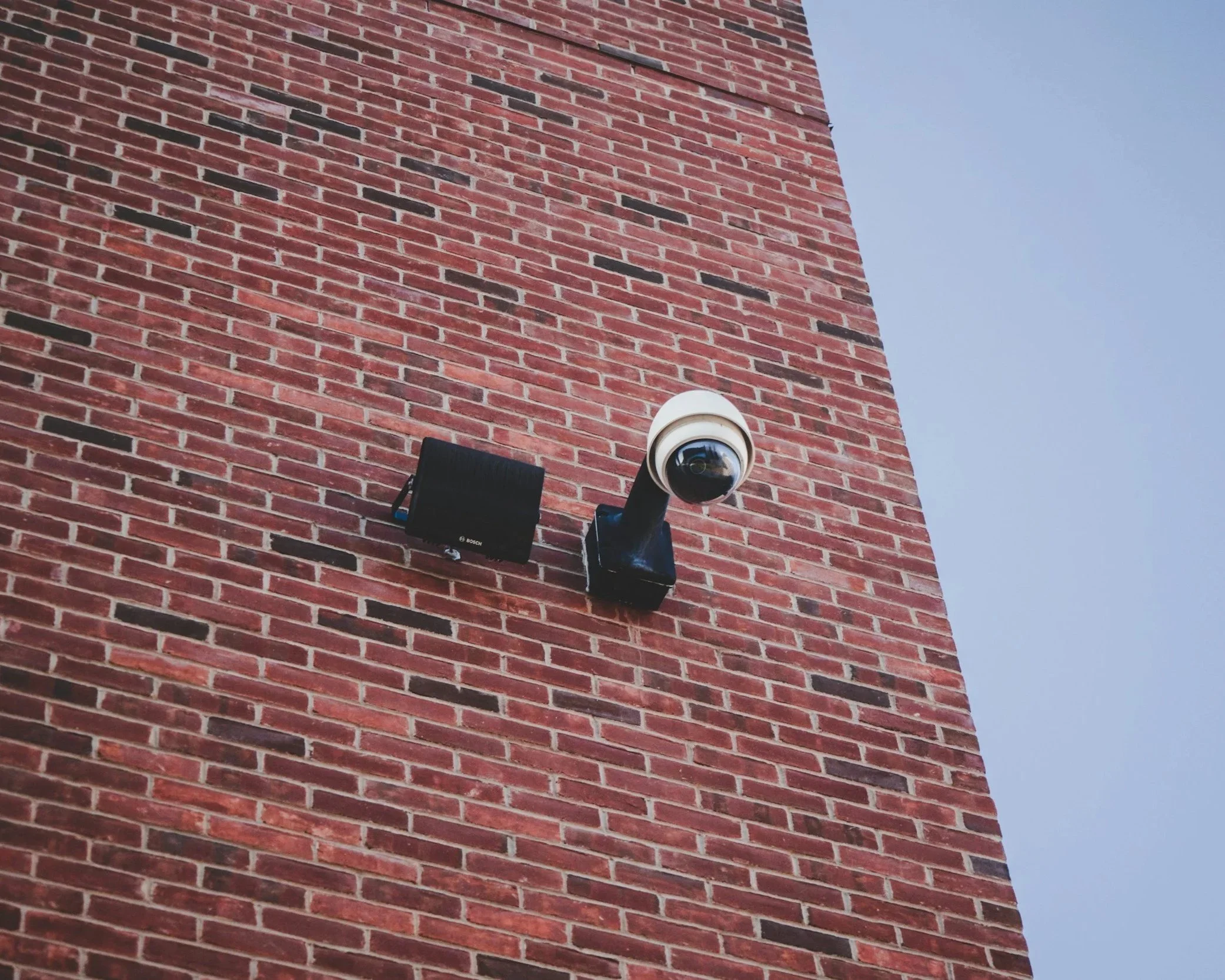 Outdoor security camera mounted on a brick building, providing reliable video surveillance