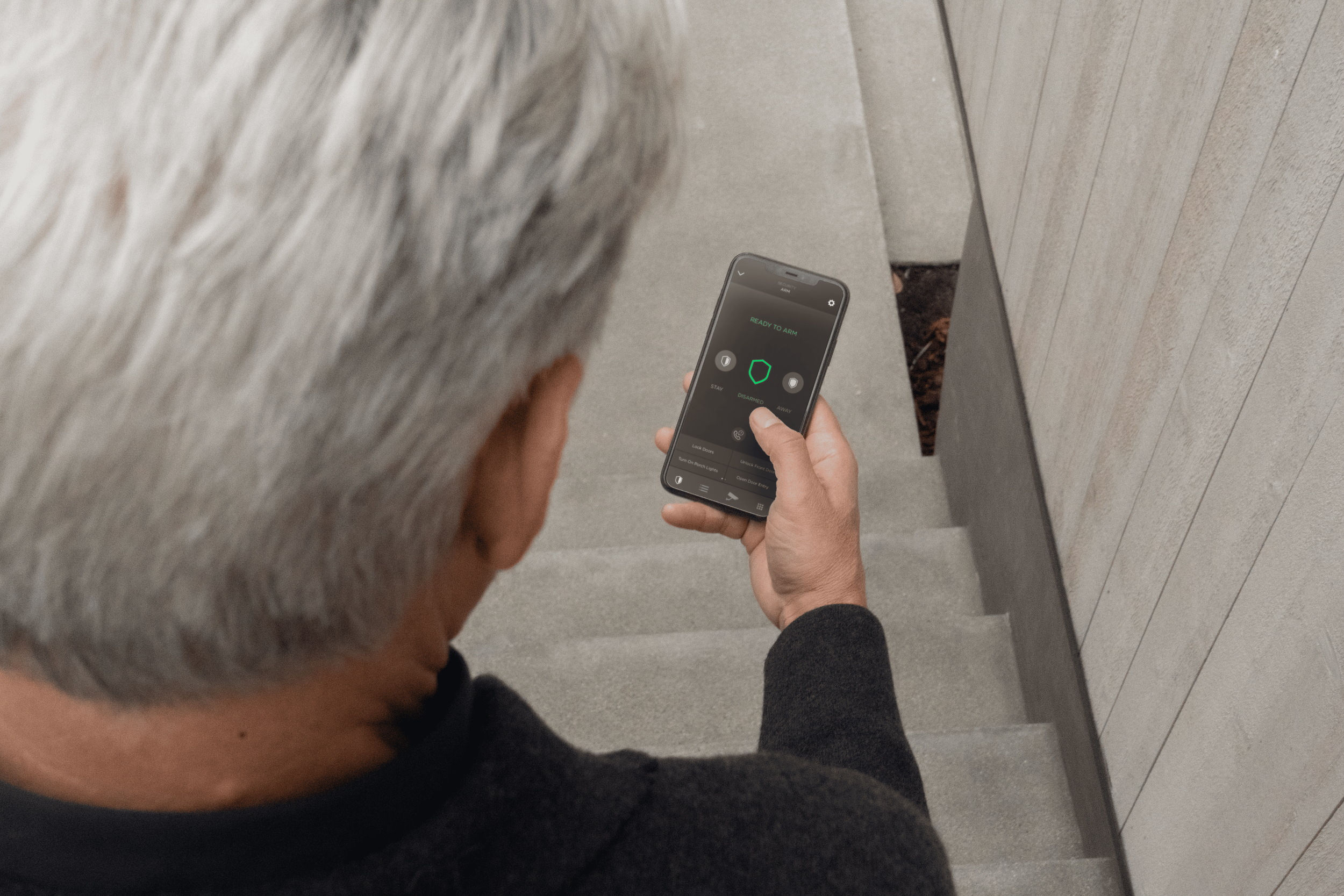 Man using a smartphone to monitor his security system indoors, demonstrating smart home surveillance technology