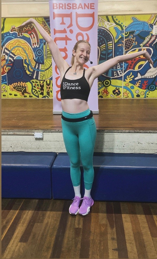 A woman in a blank tank top and leal leggings, smiling