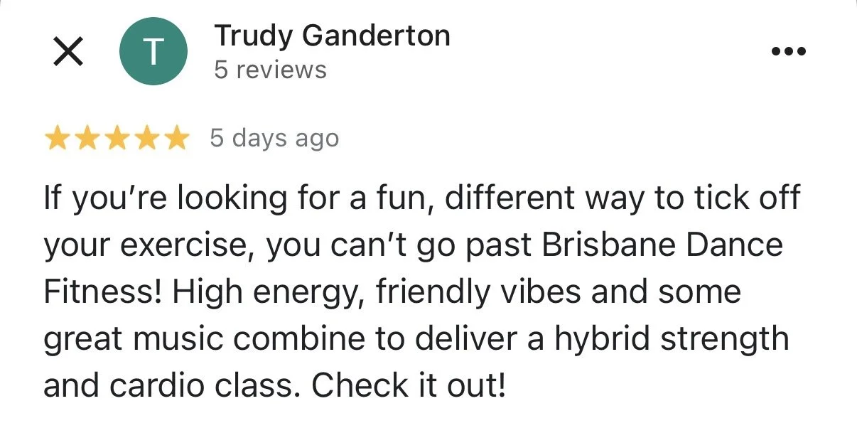 A beige stoneware vase with a single dried flower on a wooden surface, sunlight casting shadows on a white wall.