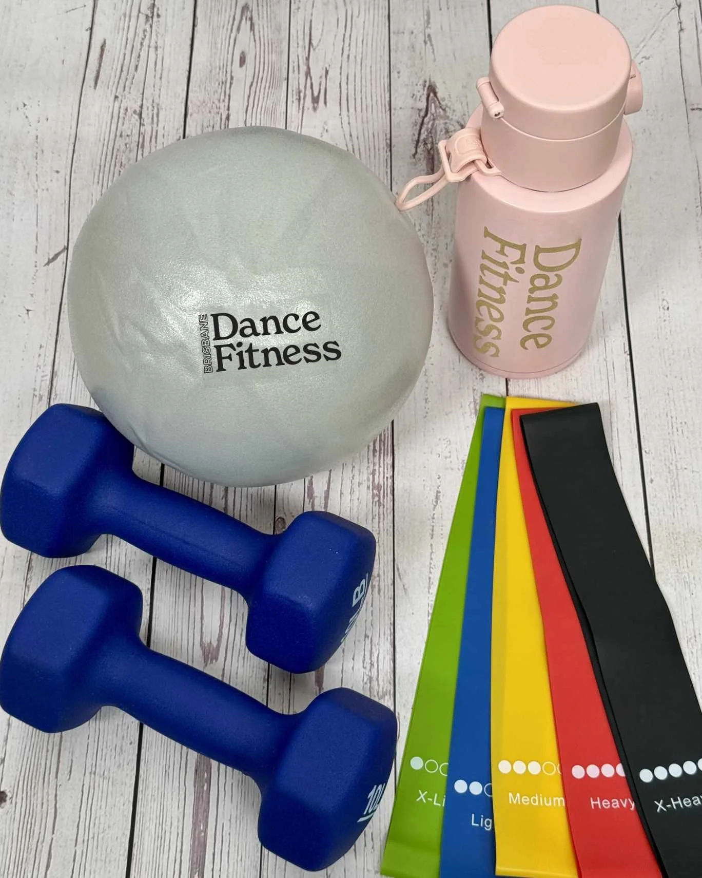 photo showing a silver pilates ball,  blue dumbbells, pink water bottle, and set of five resistance bands in primary colours