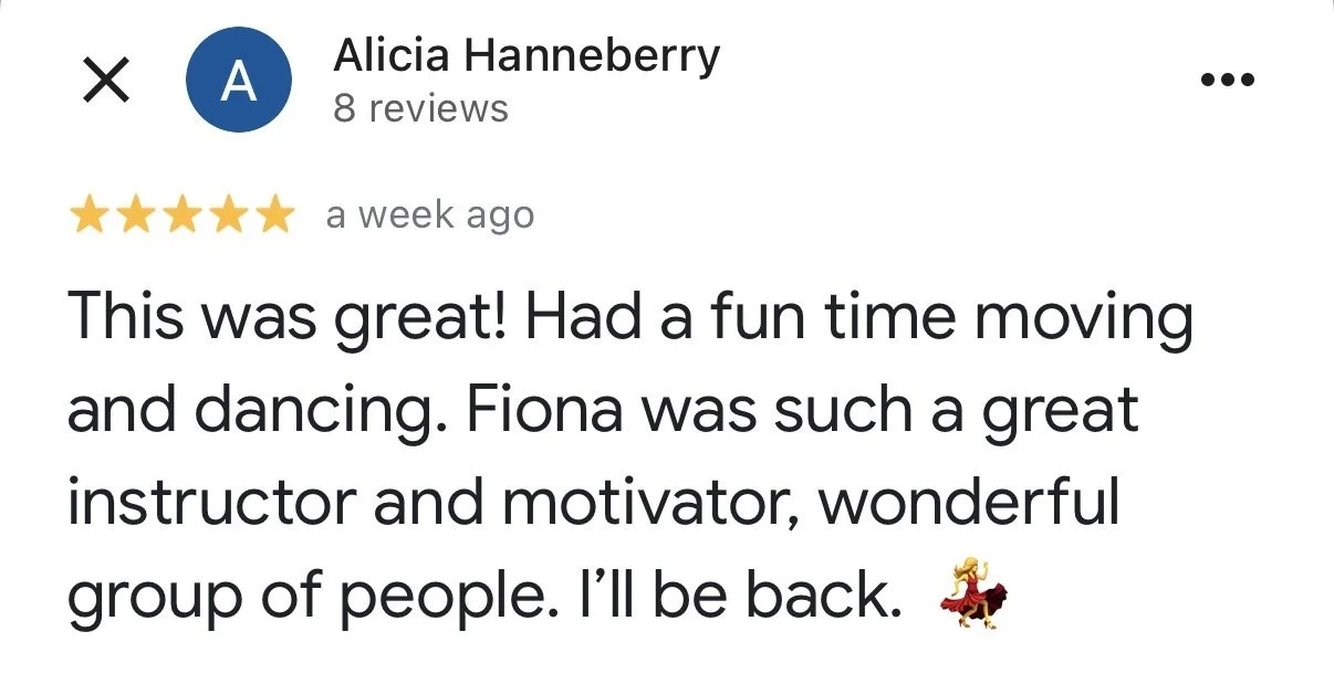 A ceramic vase with a narrow neck containing dried branches, placed on a wooden surface with soft lighting and a shadow cast on the wall behind.