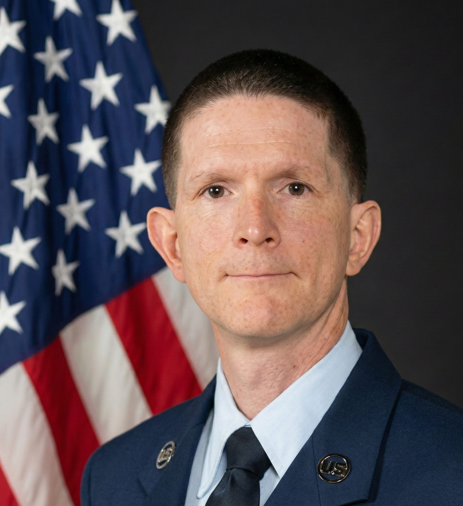 Portrait of a man in a United States Air Force uniform in front of an American flag.