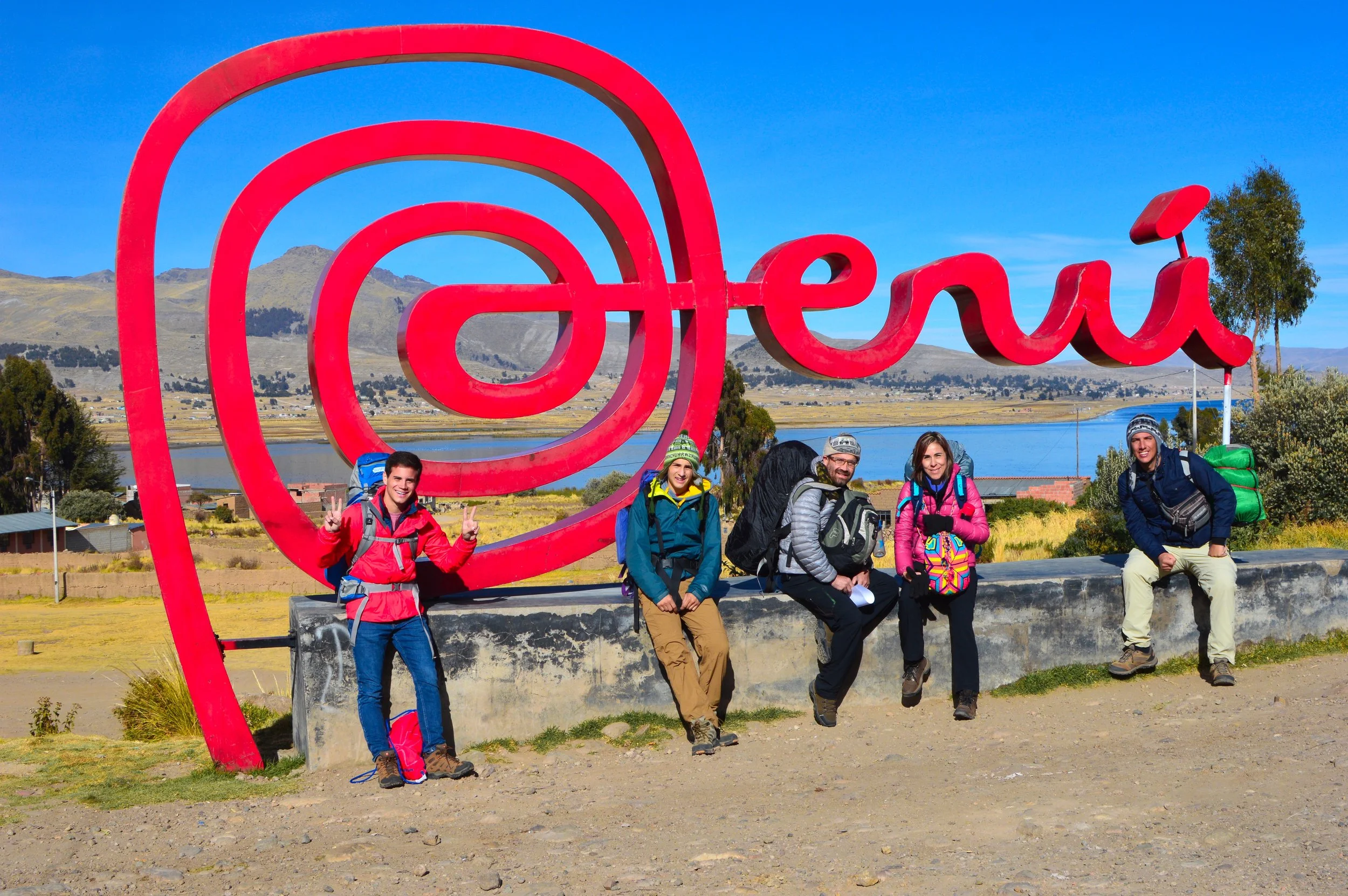 Backpackers posing at the Puno sign overlooking Lake Titicaca in southern Peru