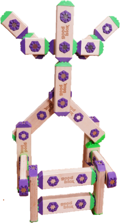 A small chair made from wooden blocks with purple flower patterns, green accents, and the words "good block" printed on some blocks.