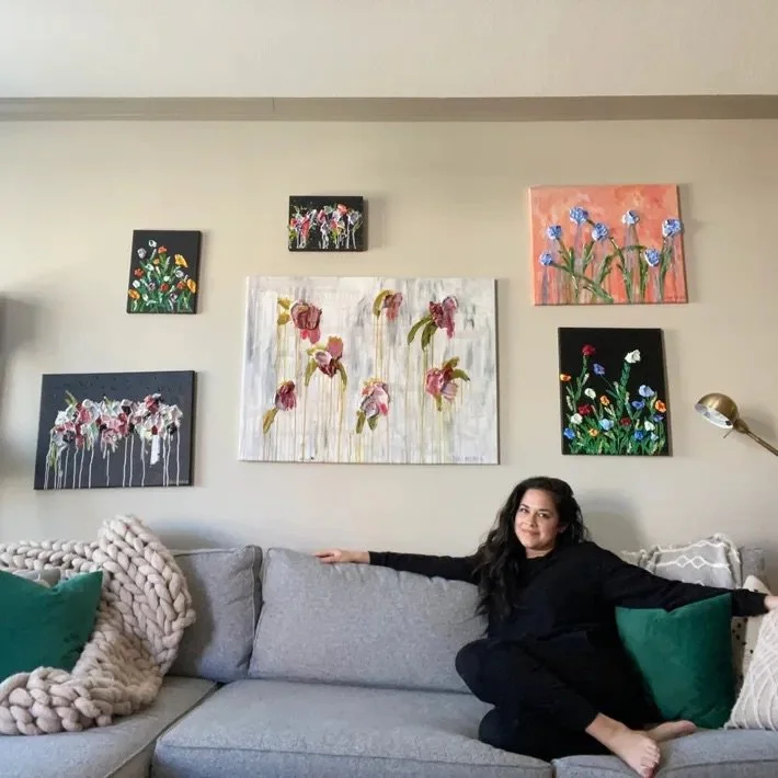 Sheila sits with her paints on the wall behind her