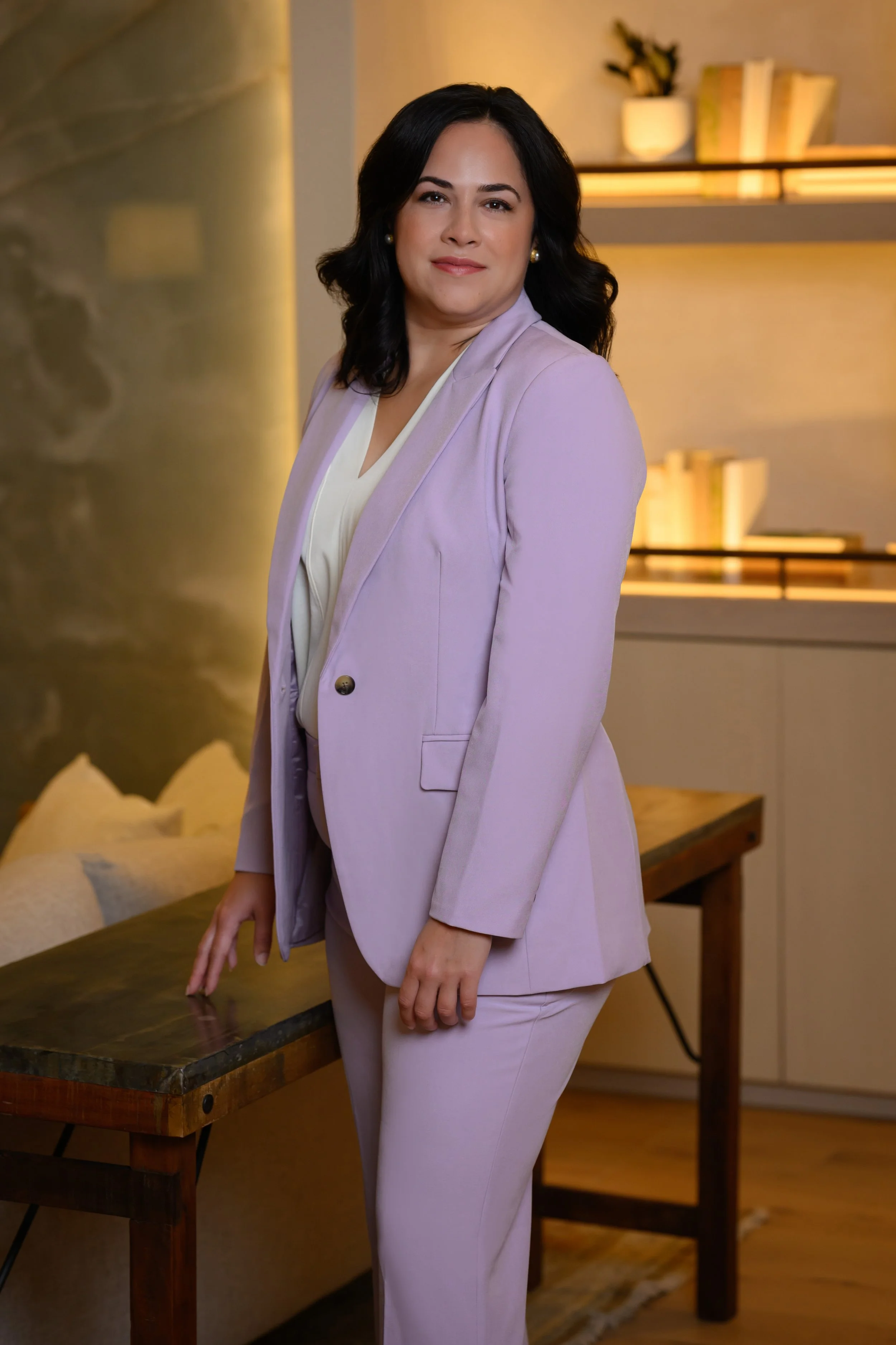 Sheila looks over her shoulder in a lavender pantsuit