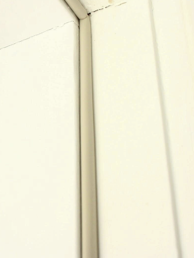 Close-up of a white corner with a narrow gap between the door and wall.