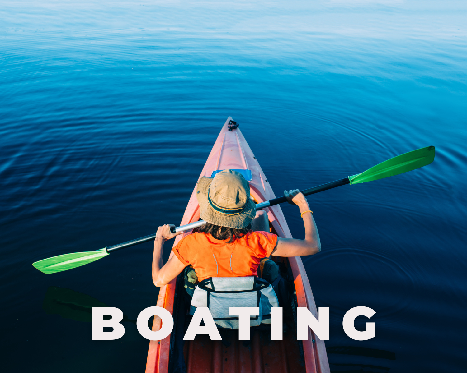 Person kayaking on calm water, wearing an orange shirt and beige hat, with the word BOATING over the image.
