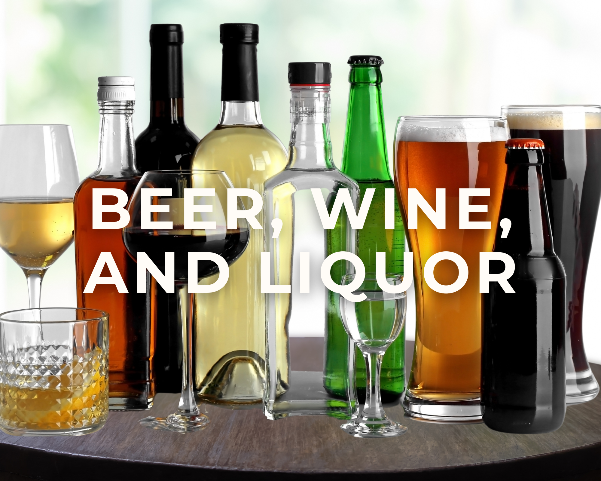 Assorted bottles and glasses of beer, wine, and liquor on a wooden table with a blurred window background.