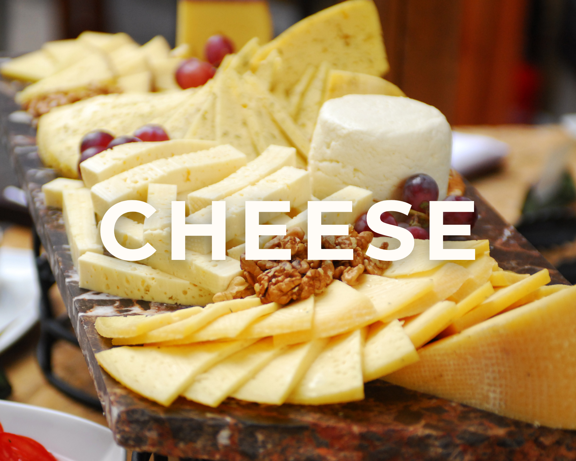 Cheese platter with various types of cheese, grapes, walnuts, and crackers arranged on a serving board.