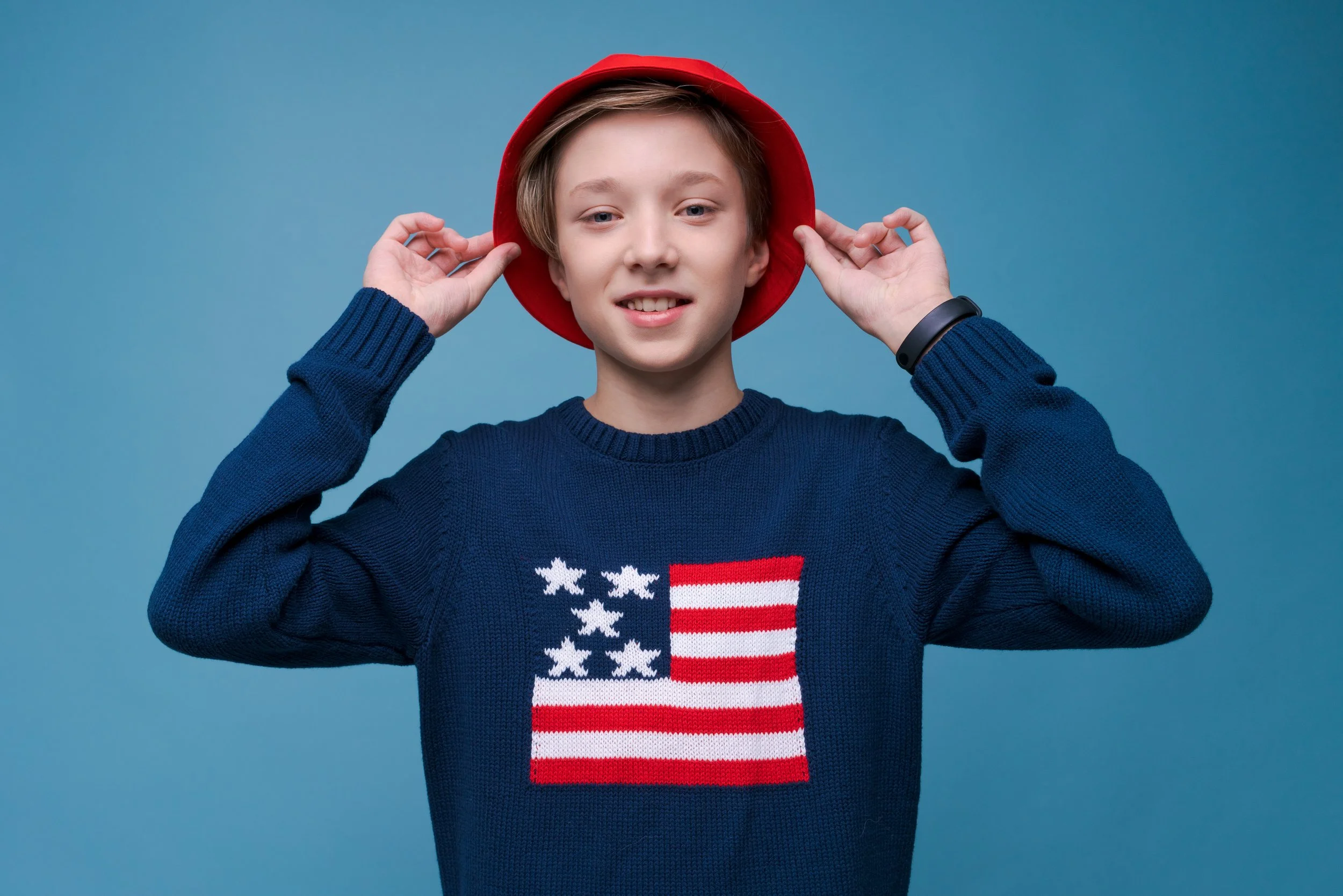 positive-teenage-boy-blue-sweater-with-usa-flag-red-hat-happy-smiling.jpg