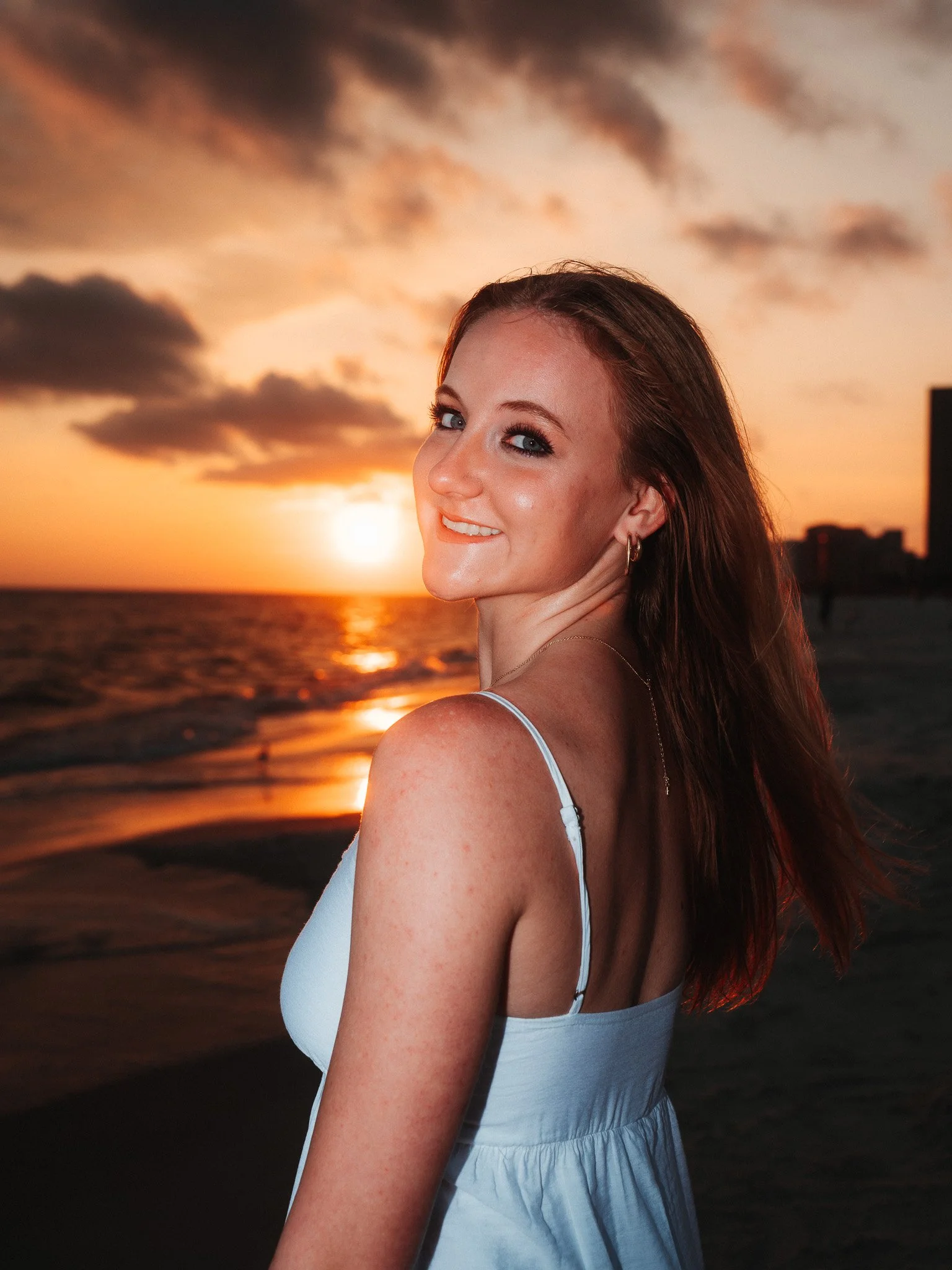 Smiling woman on the beach during sunset.