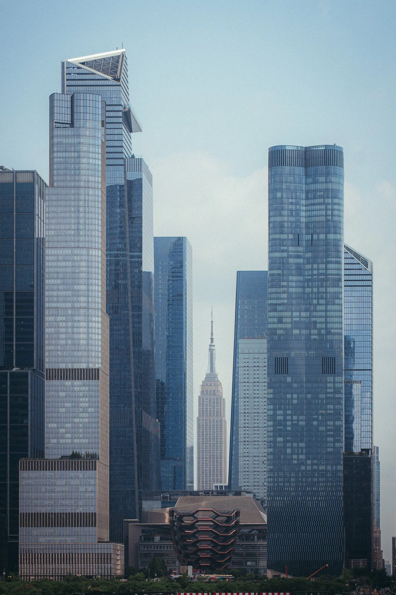 Cityscape with tall skyscrapers, including the Empire State Building in the background, and modern glass buildings in the foreground.