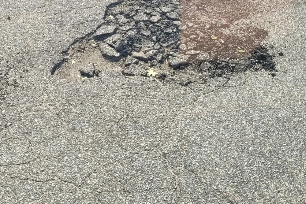 Pothole breaking up an asphalt parking lot before repair