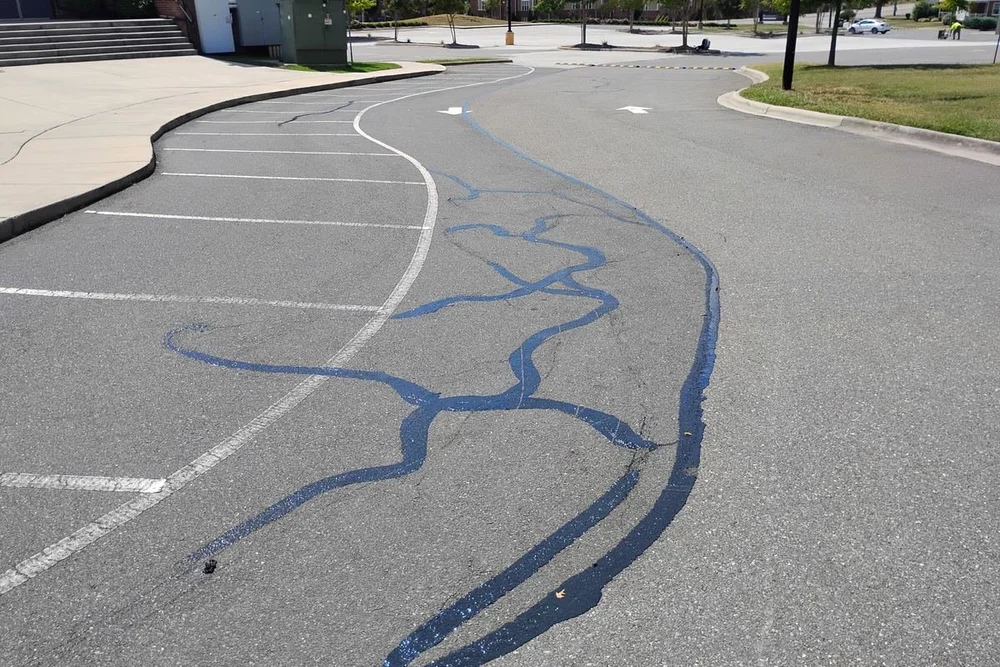 Hot rubberized crack sealant applied across a parking lot