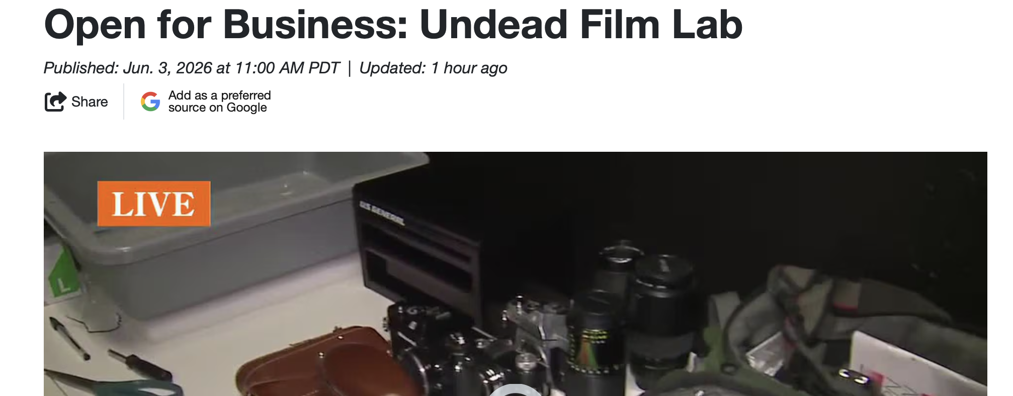 A computer setup with a black tower and multiple soda cans on a cluttered desk, with a gray container labeled 'L' and part of a keyboard visible. The image is part of a live broadcast titled 'Open for Business: Undead Film Lab.'