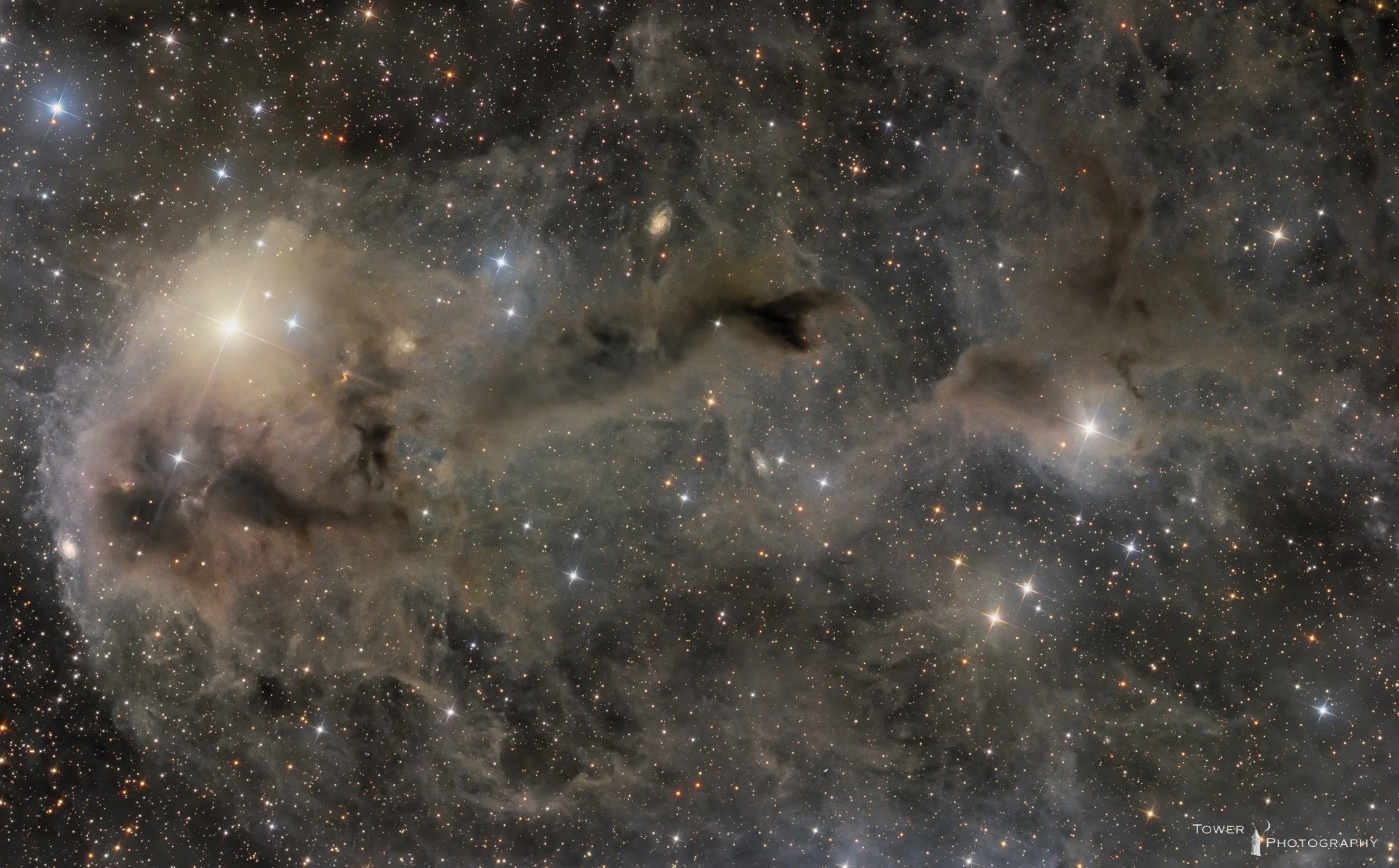 A detailed image of a star-forming region in space, displaying numerous stars, dark nebulae, and glowing gas clouds with various colors and bright spots, indicating a deep space astronomical scene.