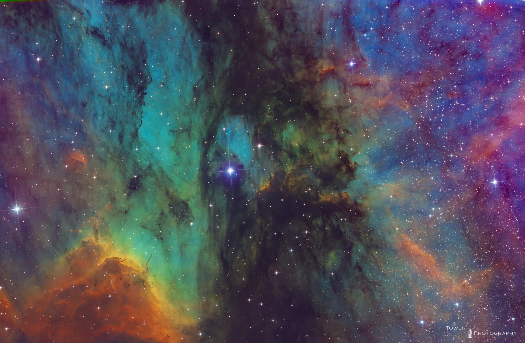 Colorful deep space image showing a nebula with stars and cosmic clouds of gas and dust in shades of blue, green, orange, and purple.
