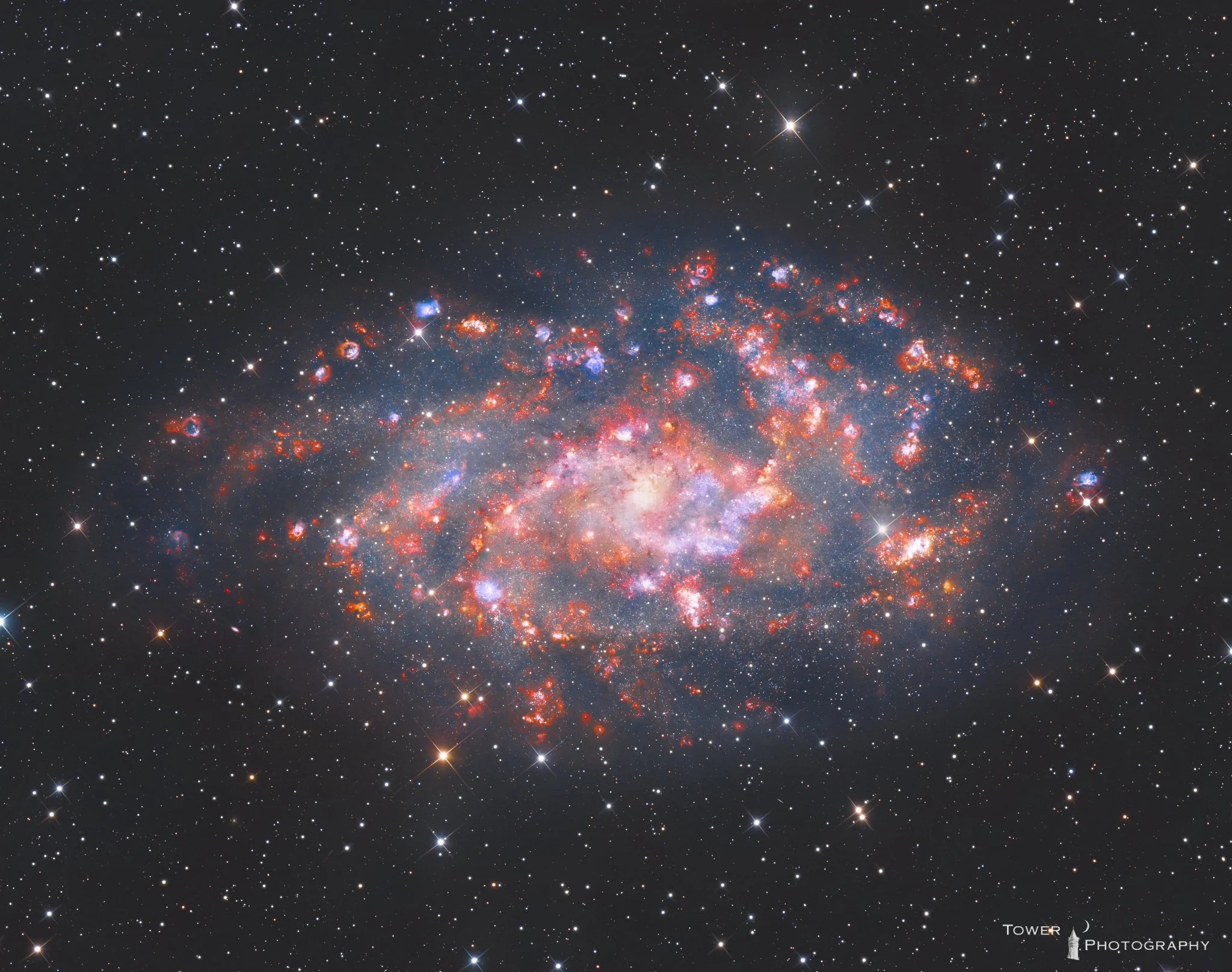 A detailed image of a galaxy with bright, colorful star clusters and dust clouds, surrounded by numerous stars in space.
