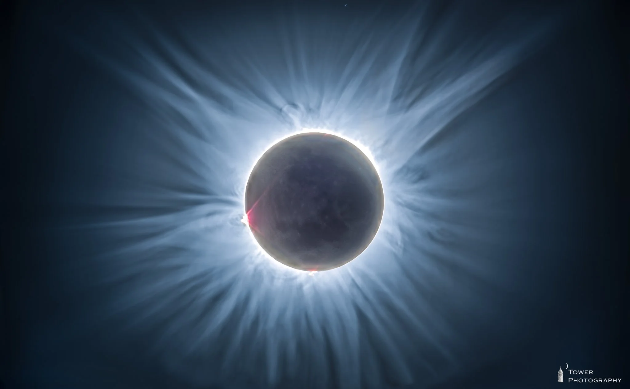 A solar eclipse with the moon covering the sun, creating a corona of bright light radiating outward.