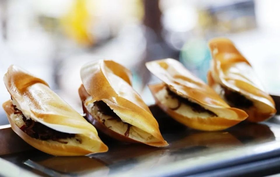 Four caramel-filled pastries on a black serving tray with a blurred background.
