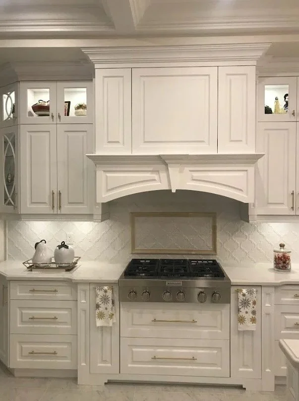 White kitchen with built-in cabinets, a gas stove, and decorative kitchen items.