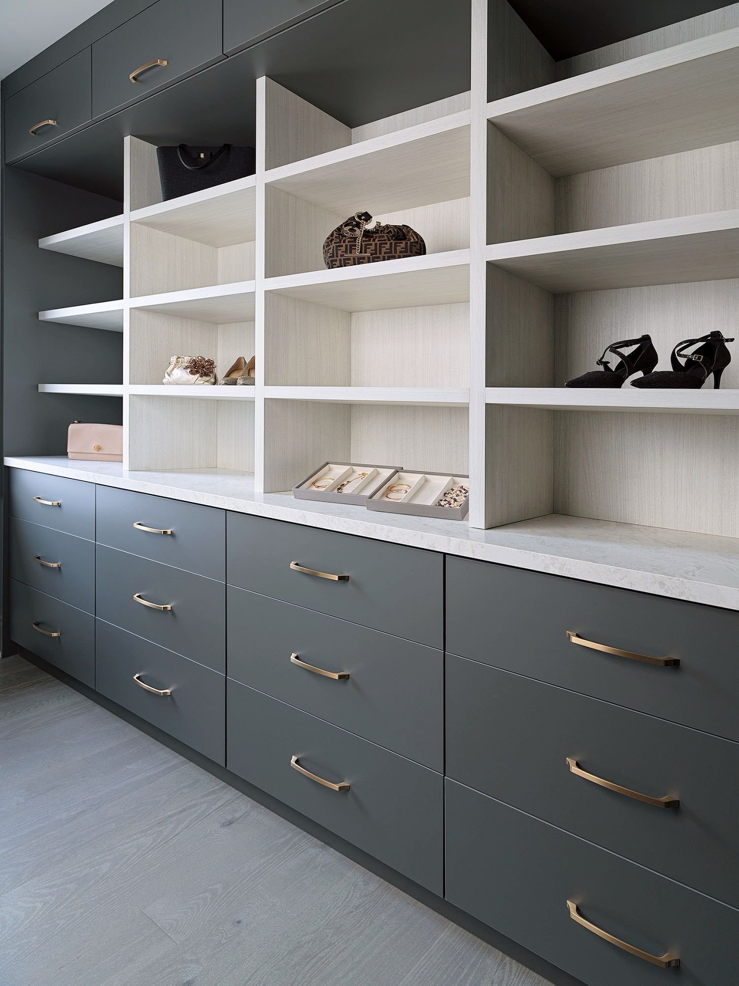 A modern closet with blue drawers and white shelves displaying jewelry, shoes, and handbags.