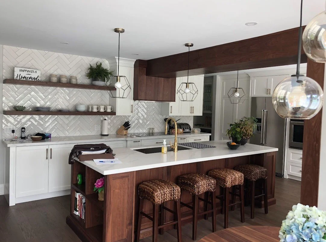 Modern kitchen with white cabinets, a white subway tile backsplash, a wood island with four upholstered bar stools, open shelves with decorative items, and pendant lighting.