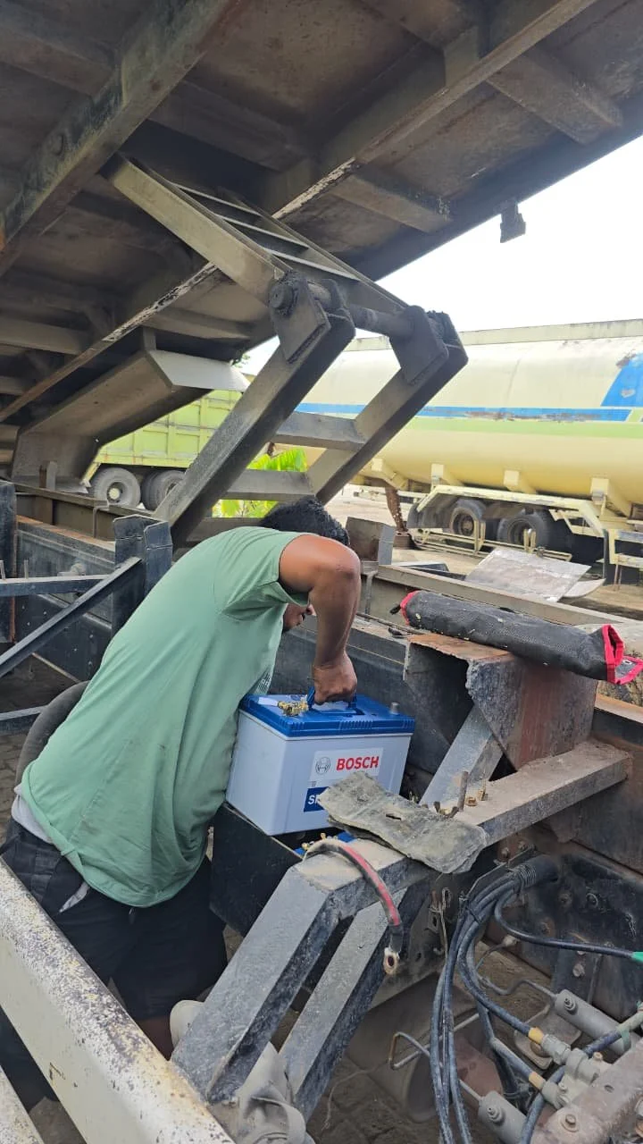 A person working under a construction structure, handling a Bosch battery.