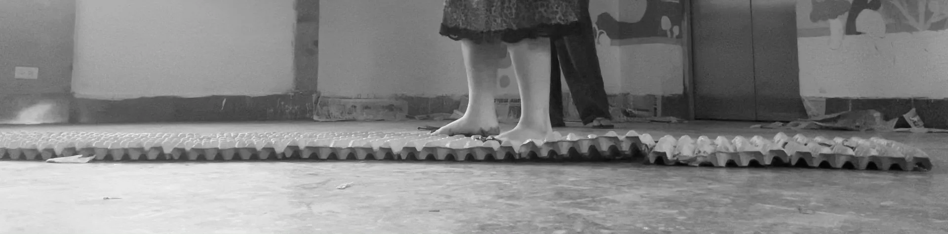 Children standing barefoot on interlocking foam mats in an indoor space, with a mural on the wall behind them.