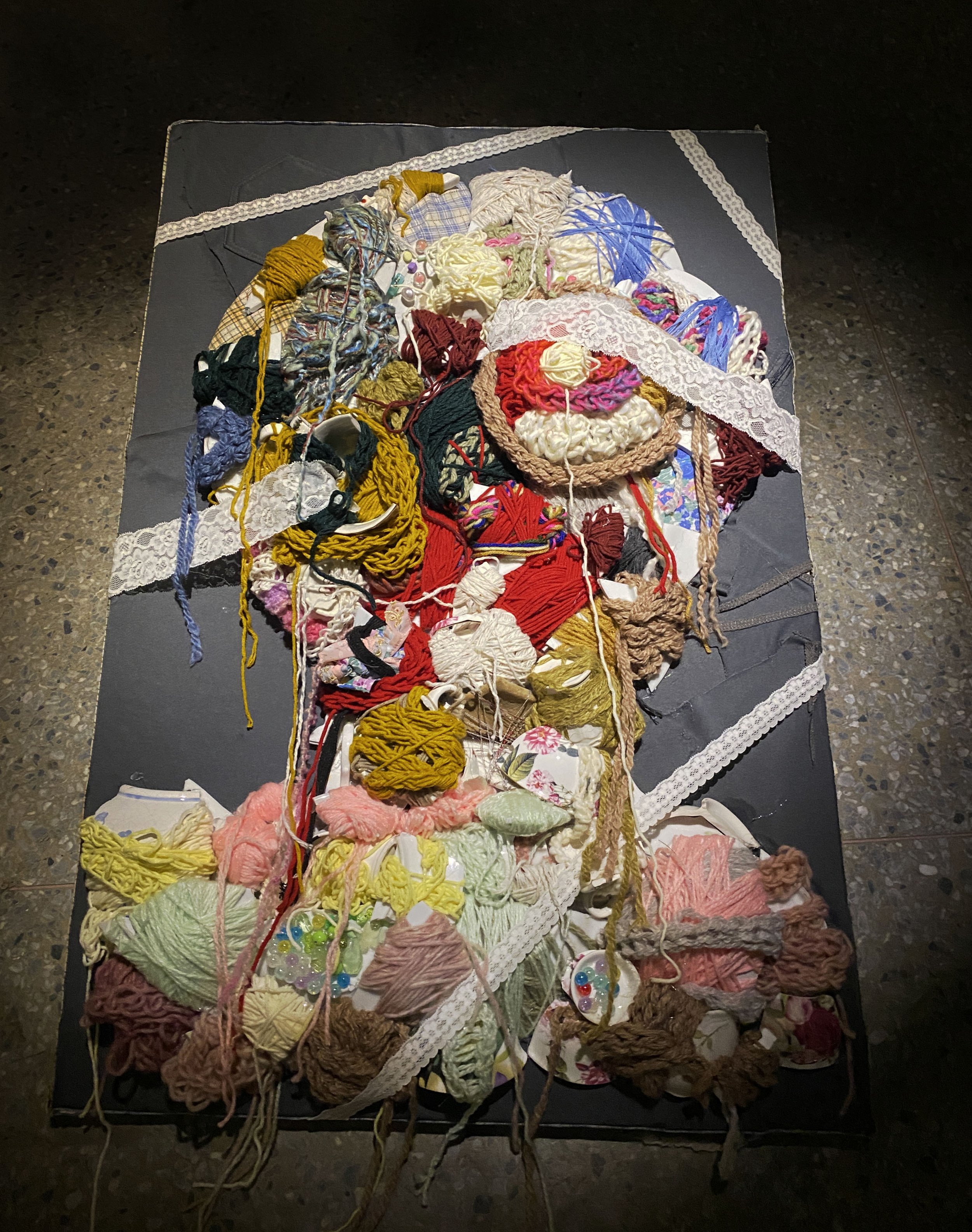 Colorful tangled yarns and fabric scraps on a black surface.