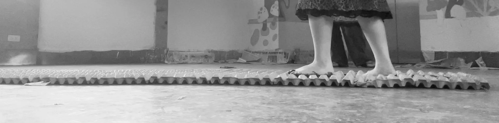 Footwear and legs of a person standing on a textured rubber mat indoors.