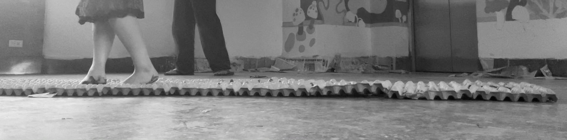People walking barefoot in a store with a textured floor mat, with some boxes and decorations in the background.