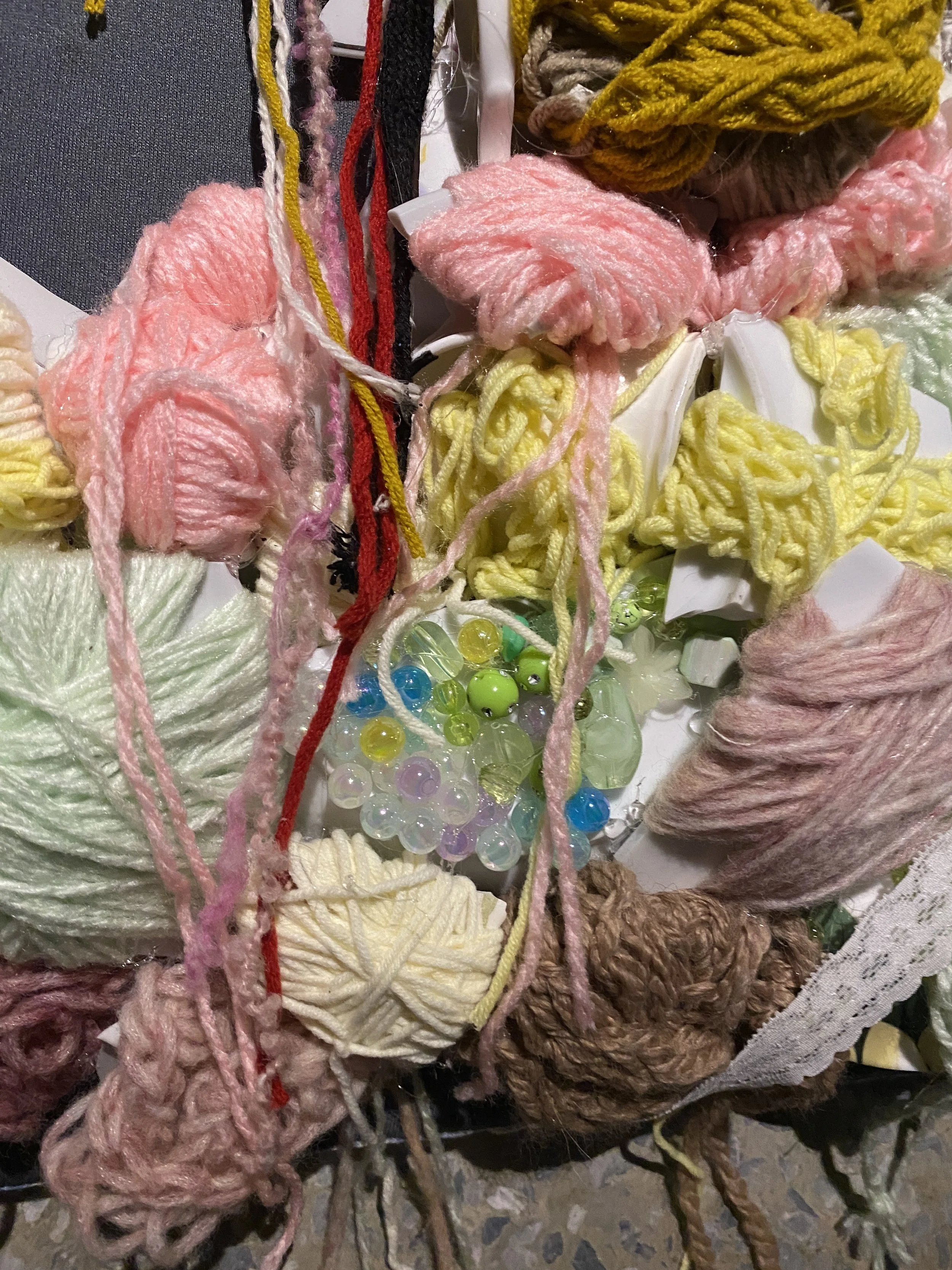 Pile of colorful yarn skeins, beads, and craft supplies.
