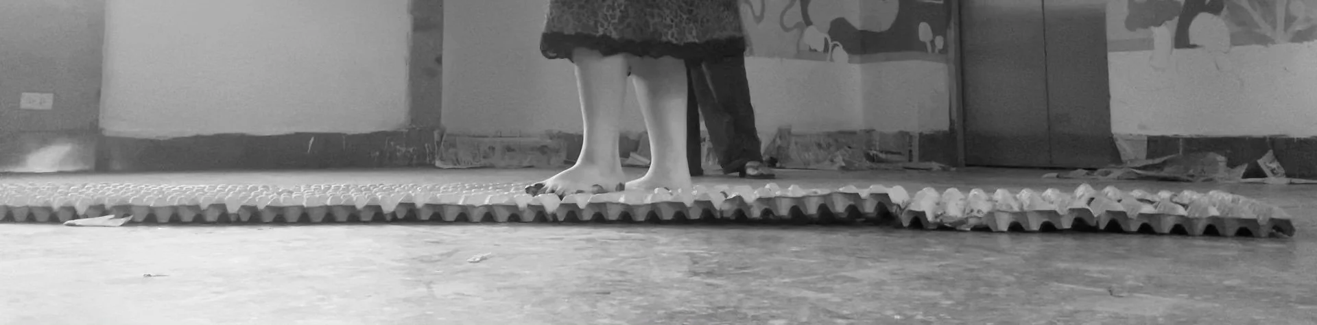 Children's bare feet standing on a textured safety mat in an indoor play area.