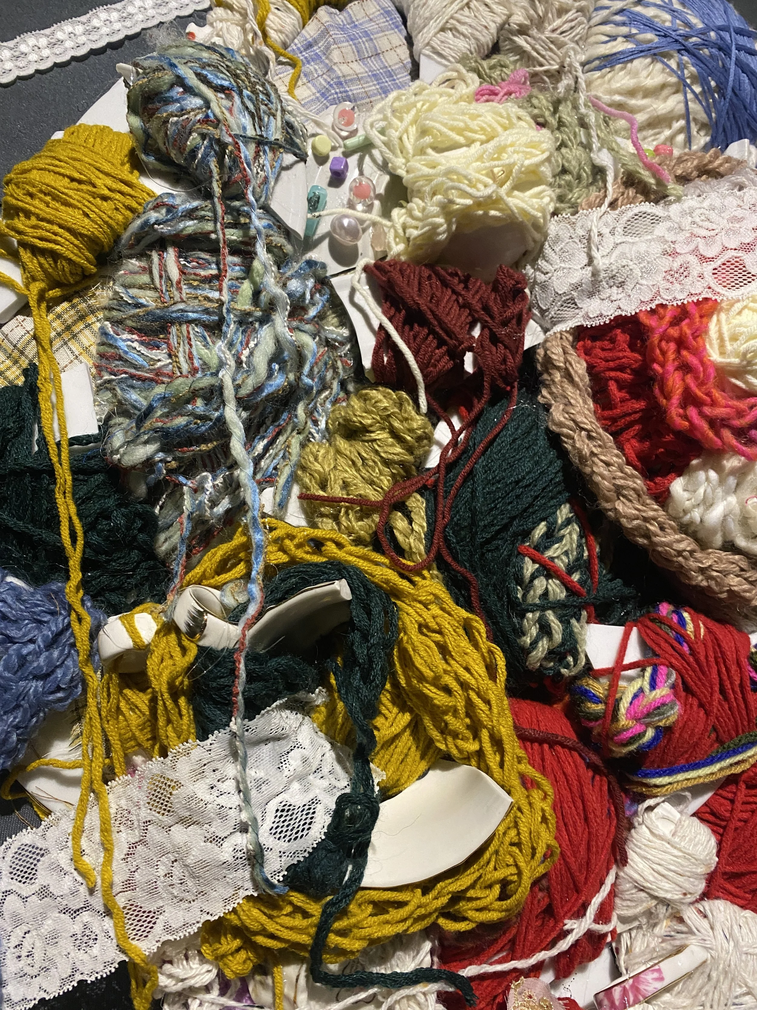 A tangled mess of various colorful yarns, knitting materials, and lace trims.