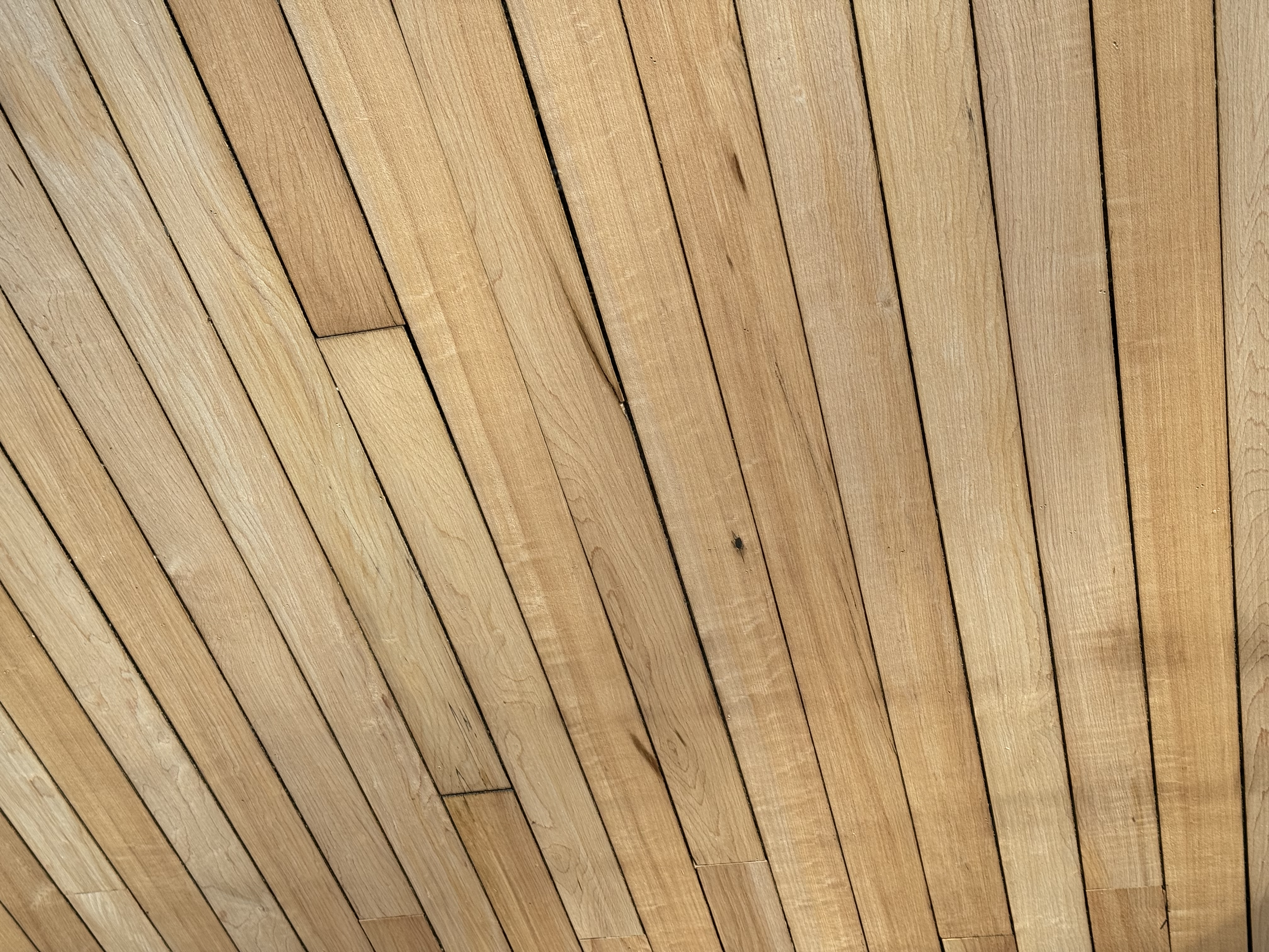 Close-up photograph of wooden floorboards arranged in parallel lines, showing the natural wood grain and color variation.