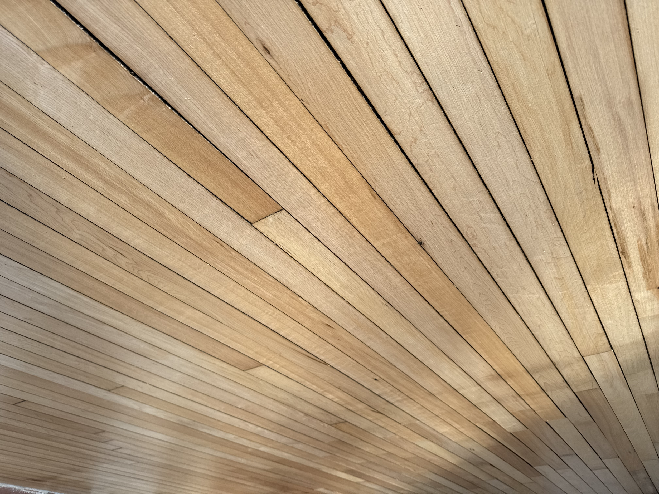 Close-up photograph of wooden floorboards arranged in parallel lines, showing the natural wood grain and color variation.