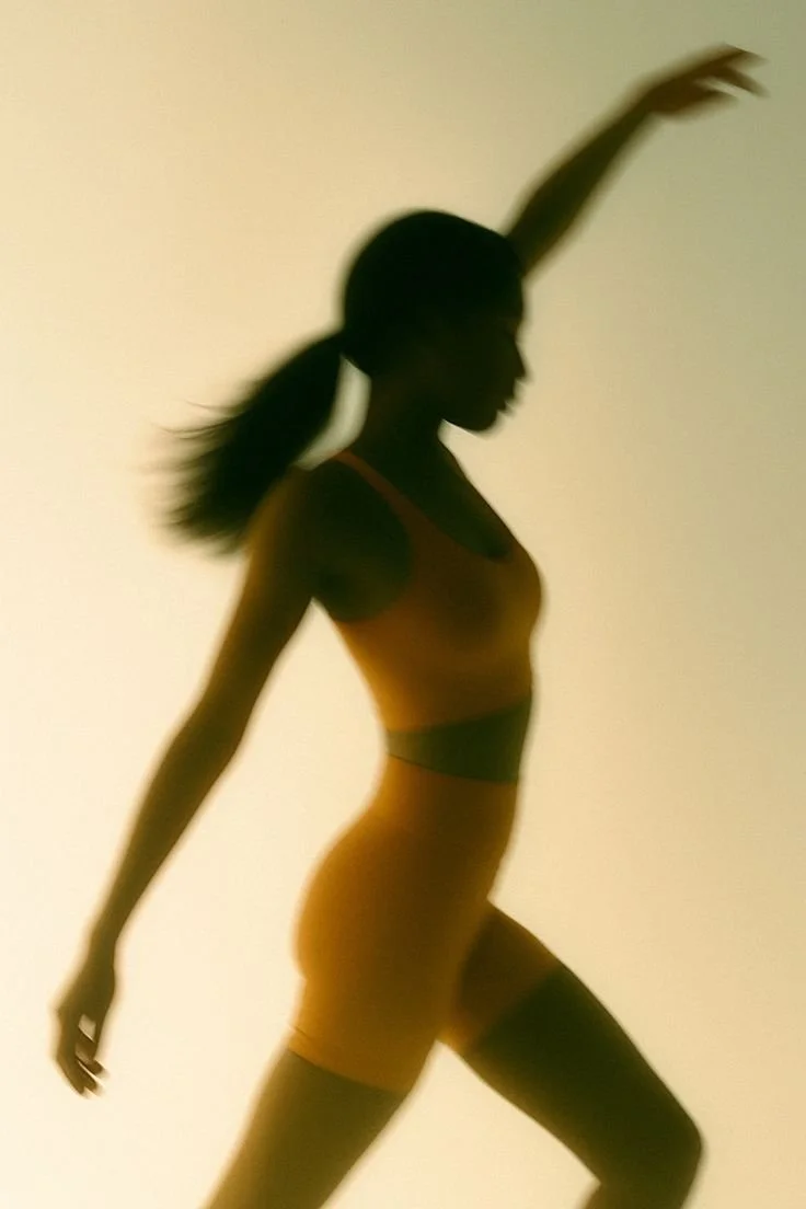 Silhouette of a woman stretching with one arm raised, wearing workout clothes, against a plain background.