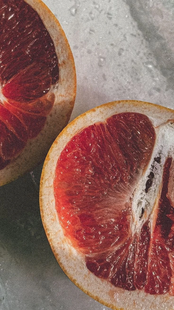 Close-up of a halved blood orange on a gray surface.