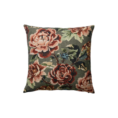 A decorative pillow with a floral tapestry pattern featuring large peony flowers in shades of pink and red, and green leaves on a dark background.