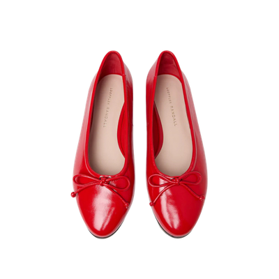 Red ballet flats with bows on a black background.