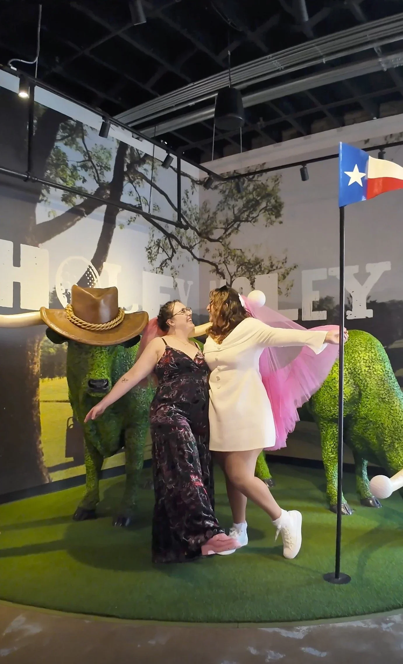 two brides pose for wedding content creator at Holey Moley