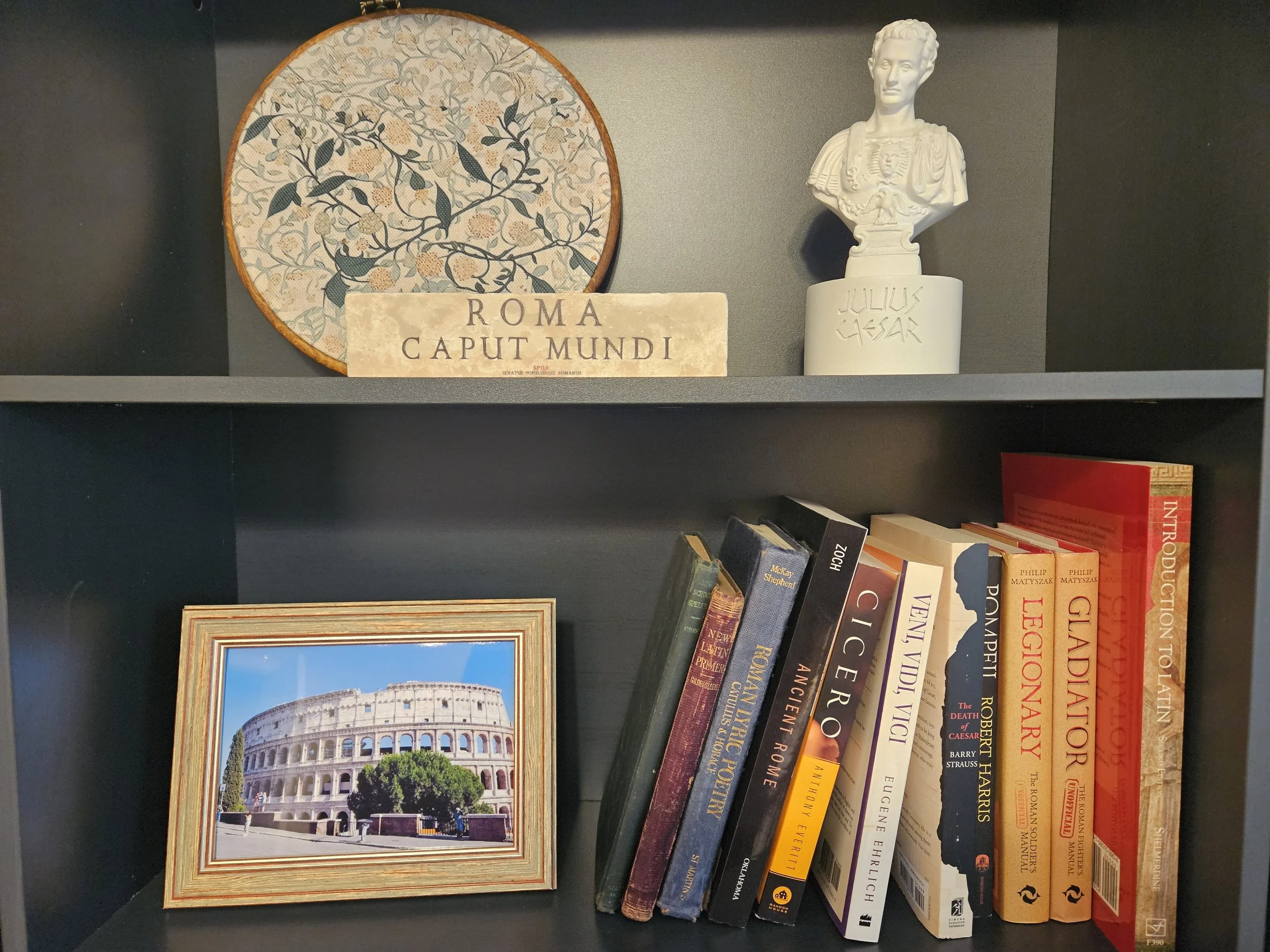 A row of old, worn books on a shelf, with handwritten labels and numbers on their spines for cataloging.