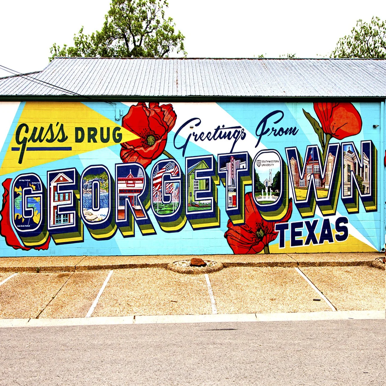 Colorful mural on a building with the text 'Greetings From Georgetown, Texas' and various town images inside the letters, decorated with large red poppies.