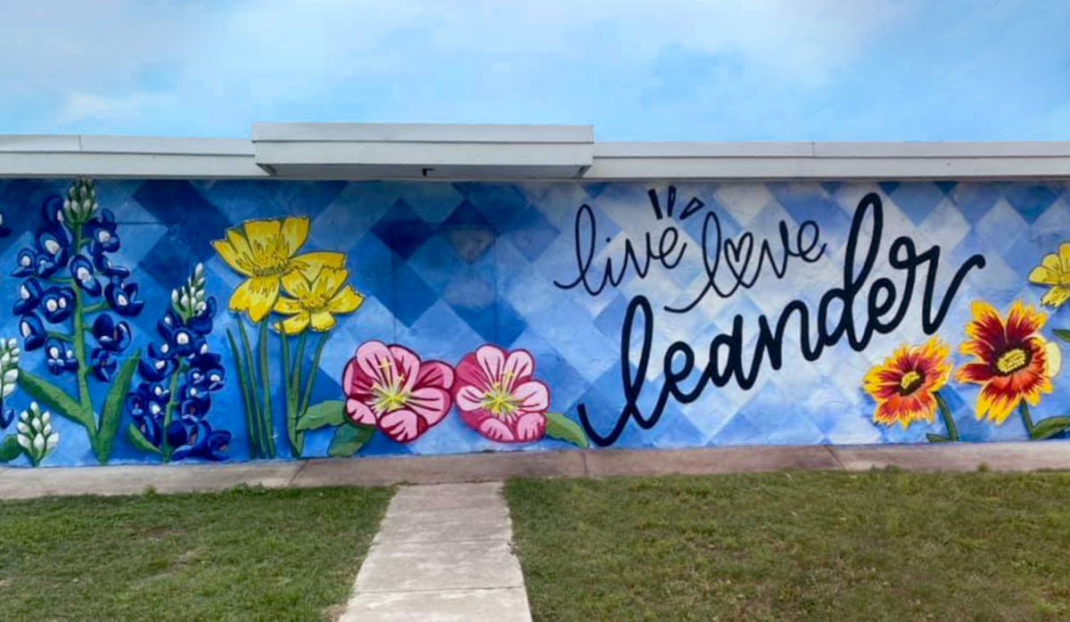 A colorful mural on a blue wall featuring flowers, with the words "live love lender" written in black cursive and stylized text.