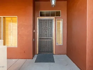 Entrance with a black security door, a small window to the right, a larger window to the left, and an orange exterior wall.