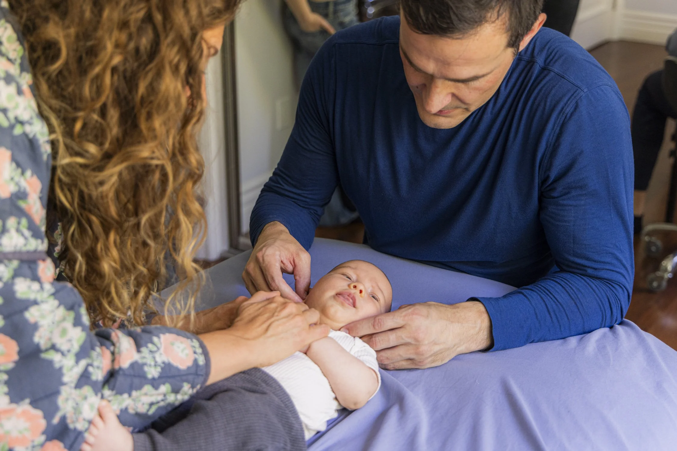 Jimmy Clabots providing Infant CranioSacral Therapy to a baby with the baby's mom holding the baby's arms.