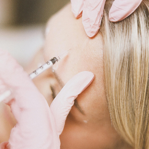 A healthcare professional administering an injection to a person's forehead.